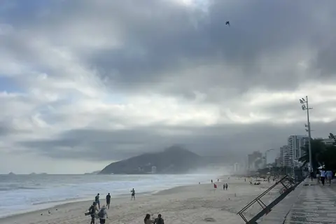 Ruhiger Strand am Morgen und Promenade mit Mosaikpflaster unter bewölktem Himmel