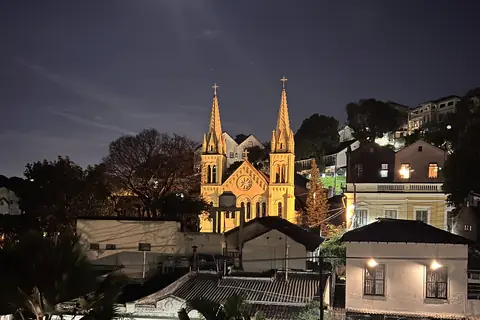 Église aux deux clochers illuminée la nuit au-dessus des toits d'un vieux quartier de Rio