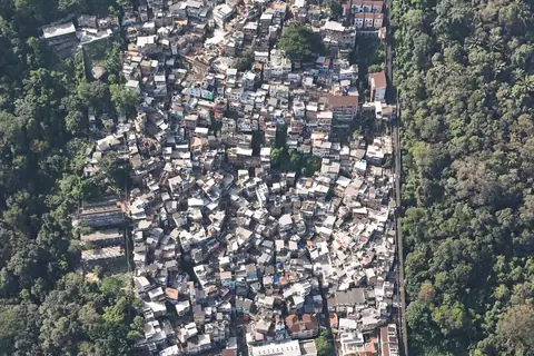 Quartier dense à flanc de colline entouré de forêt, vu d'en haut