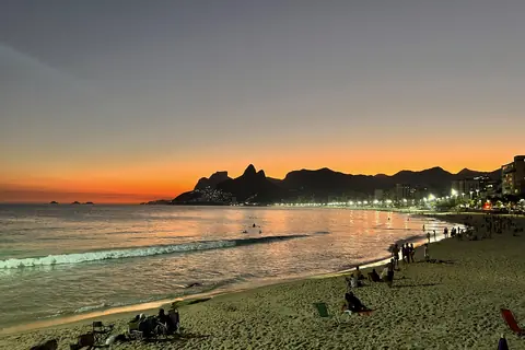 Orangefarbener Sonnenuntergang über dem Strand von Ipanema mit dem Morro Dois Irmãos in der Ferne